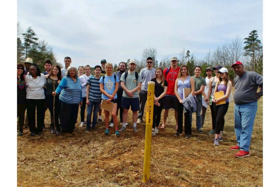 group photo of 20+ advocates outside in a field with a post that says "pipeline"