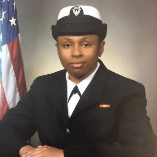 photo of India Kager, dressed up in a navy uniform with the U.S. flag in the background