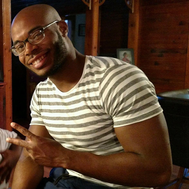 photo of Marcus David Peters, a young Black man smiling and doing the peace hand sign.