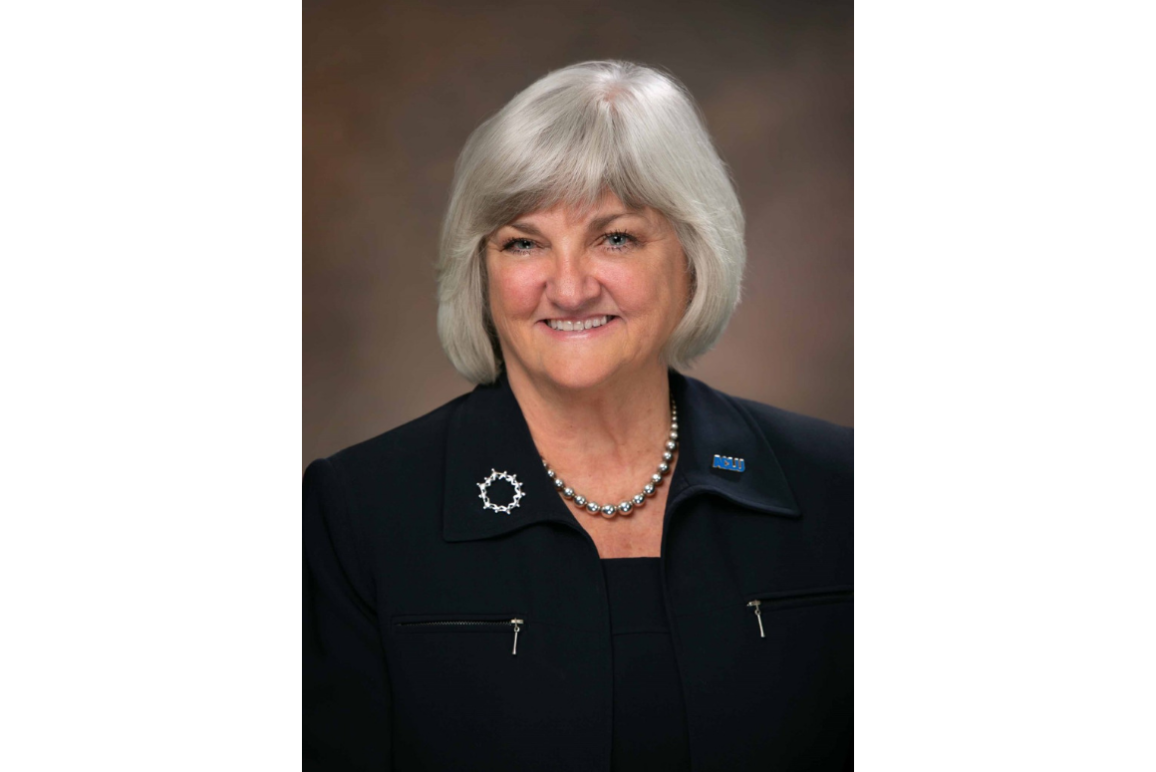 portrait of our executive director Claire Gastanaga, with shoulder length silver hair, round face, blue eyes, and wearing all black.