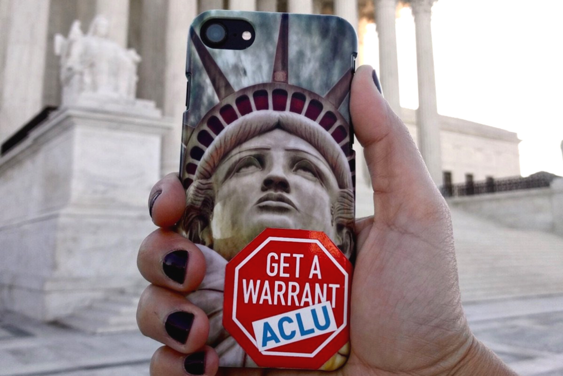 hand holding a phone with Lady of Liberty case and an ACLU Get a Warrant sticker