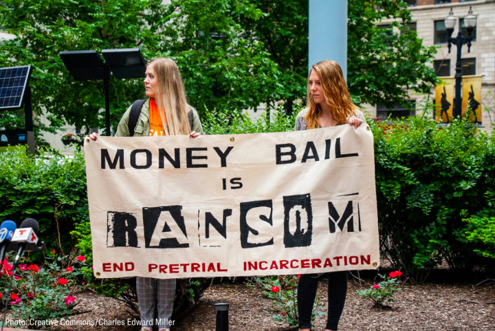 two woman holding a banner that said "money bail is ransom. End pretrial incarceration."
