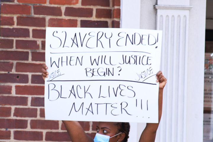 Black woman holding a protest sign that says "slavery ended, when will justice begin? Black lives matter!!!{"